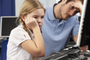 Generic image of child and teacher at a PC