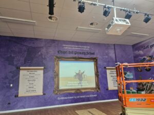 Image showing a school hall with projector projecting onto a framed area of a wall.