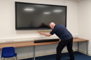 AV Solutions - Cablers Engineer, installing a sound bar under an Interactive Screen